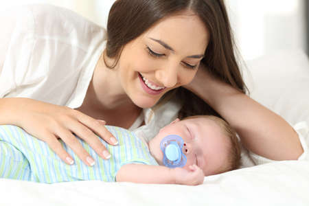 Proud mother watching her baby sleeping on a bed at home