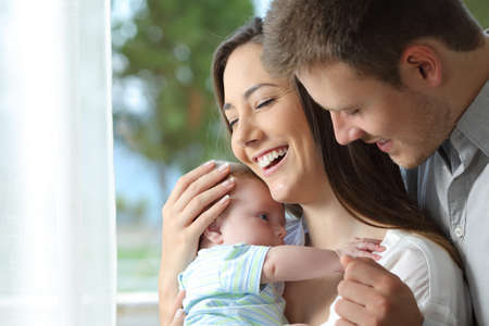Portrait of a proud parents holding their baby at homeの写真素材