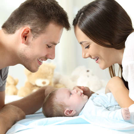 Proud parents watching their son on a bed at homeの写真素材