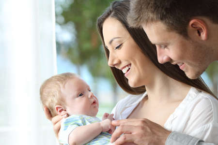 Proud parents holding and playing with their baby at homeの写真素材