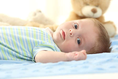 Portrait of a baby lying on a bed and looking at youの写真素材