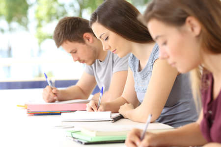 Three students taking notes during a class in a classroom