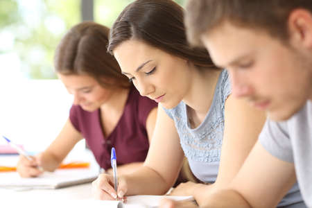 Close up of three serious students taking notes in a classroomの写真素材