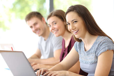 Portrait of three happy students looking at you at classroomの写真素材