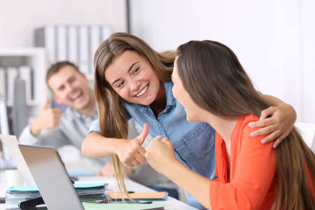 Happy colleagues congratulating to a successful employee after achievement at officeの写真素材