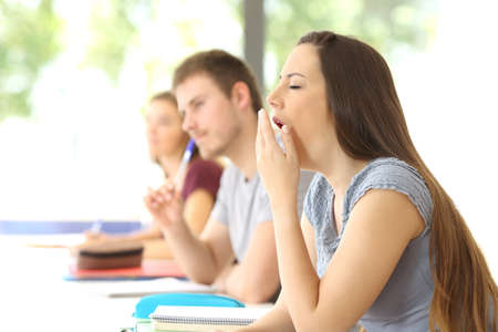 Side view of a bored student yawning during a class in a classroomの写真素材