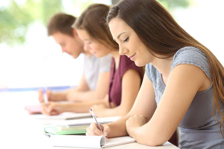 Side view of three concentrated students studying taking notes at classroomの写真素材
