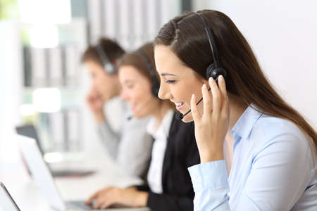 Happy teleoperator working at call center with other employees in the background