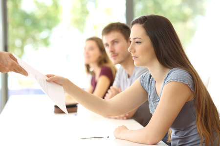 Student receiving an exam from the teacher at classroomの写真素材