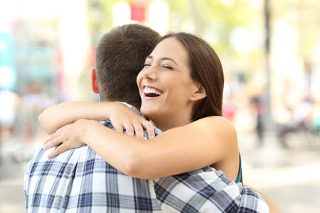 Happy couple or friends hugging after meeting on the streetの写真素材