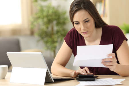 Attentive woman calculating accountancy sitting in a desk at homeの写真素材