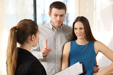 Bad real estate agent attending to discontent customers in a house interior