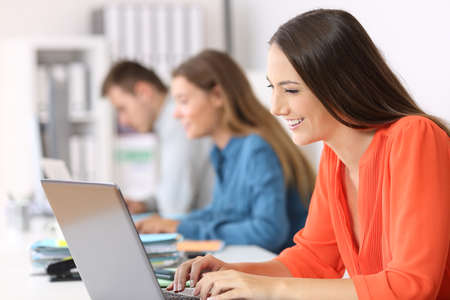 Side view portrait of a businesswoman typing in a laptop at officeの写真素材