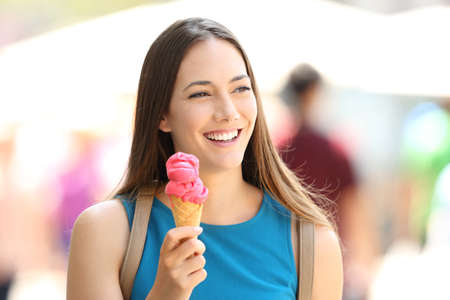 Happy girl walking and holding a strawberry  ice cream in the streetの写真素材