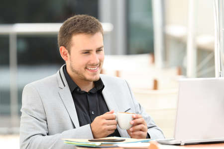 Portrait of a happy executive watching on line content sitting in a coffee shopの写真素材