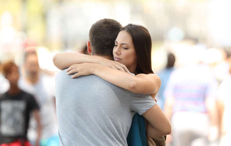 Discontent woman hugging her couple with problems on the streetの写真素材