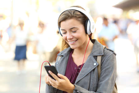 Happy teenager listening music wearing headphones on the streetの写真素材