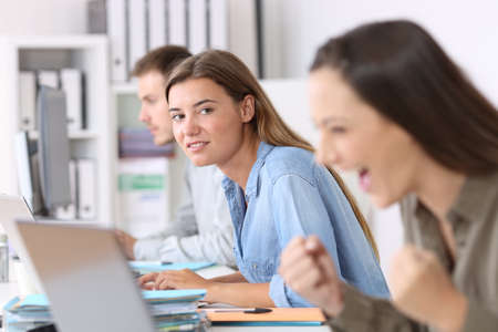 Portrait of a envious employee looking at a successful colleague at officeの写真素材