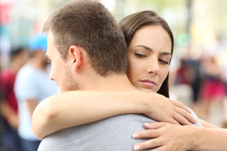 Discontent girlfriend hugging her partner on the streetの写真素材