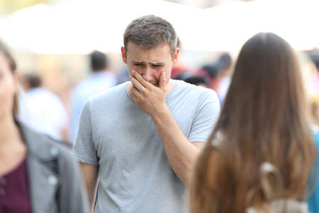 Front view portrait of a sad boy walking on the street being ignored by the crowdの写真素材