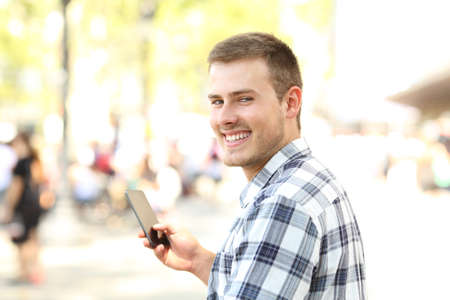 Man holding mobile phone looking at you on the streetの写真素材