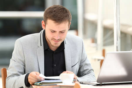Concentrated executive reading documents sitting in a coffee shopの写真素材