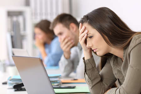 Portrait of three worried employees reading bad news on line at officeの写真素材