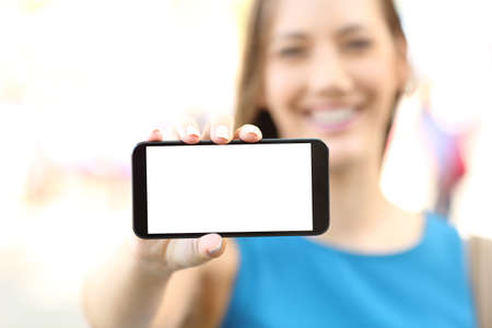 Close up of a happy female showing a blank horizontal phone screen on the streetの写真素材