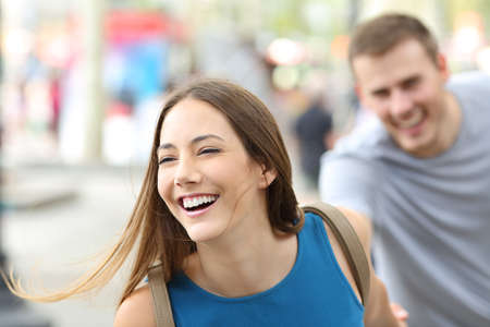 Funny couple of teenagers running towards camera on the streetの写真素材