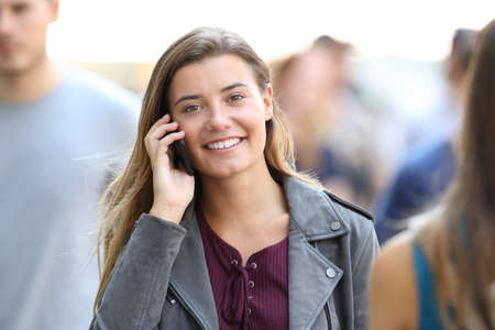 Front view portrait of a happy lady calling on the phone looking at you on the streetの写真素材