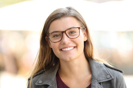 Front view portrait of a beautiful satisfied girl wearing eyeglasses on the streetの写真素材
