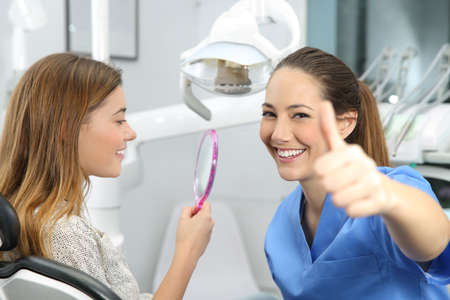 Portrait of a satisfied client and dentist checking dental results at officeの写真素材