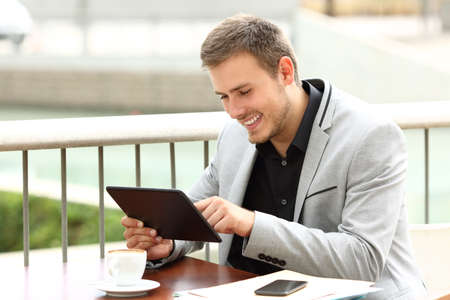 Single executive works on line with a tablet sitting in a coffee shopの写真素材