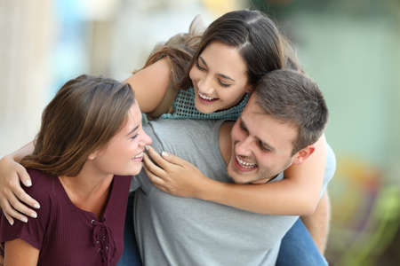 Three happy friends meeting and joking together on the streetの写真素材