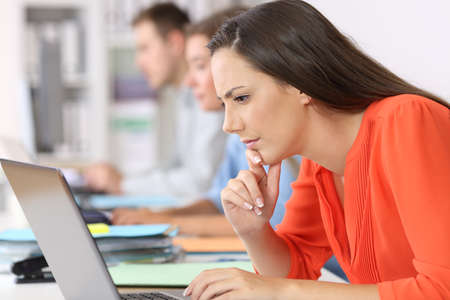 Side view portrait of a pensive businesswoman watching on line content at officeの写真素材