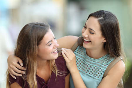Portrait of two happy friends meeting and joking on the streetの写真素材