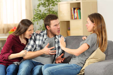 Roommates arguing and shouting each other on a sofa at homeの写真素材