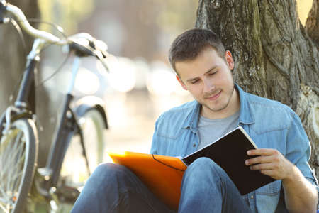 Single student studying reading notes outdoors sitting in a parkの写真素材