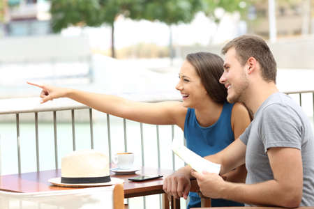 Couple ot tourists pointing locations sitting in a coffee shopの写真素材