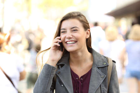 Teen laughing while talking on the phone on the streetの写真素材