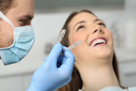 Close up of a dentist hand showing an implant to a patient in an officeの写真素材