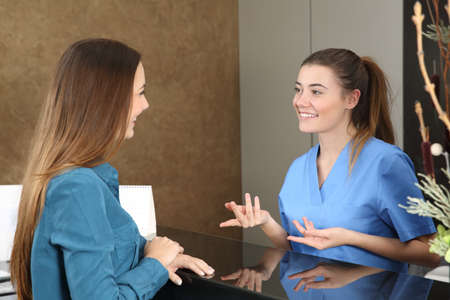 Happy dentist or nurse attending a patient in a consultationの写真素材
