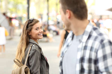 Strangers girl and guy flirting looking each other on the streetの写真素材