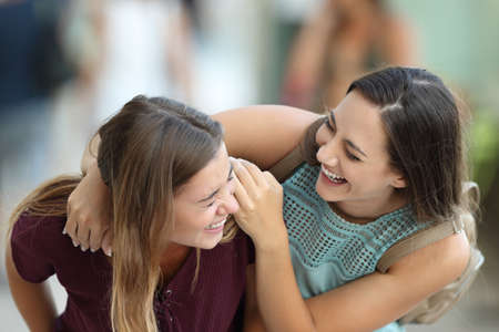 Two happy friends meeting and joking laughing on the streetの写真素材