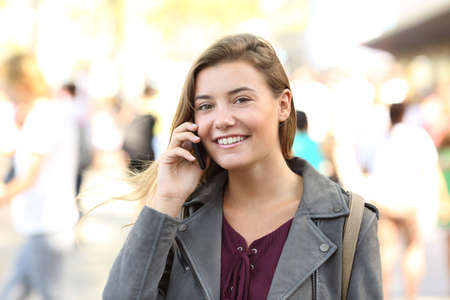Teen smiling looking at you on the phone on the streetの写真素材