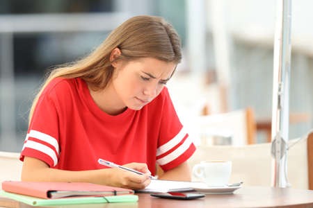 Single confused student studying reading notes sitting in a barの写真素材