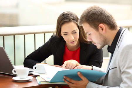 Two executives coworking analyzing documents sitting in a barの写真素材