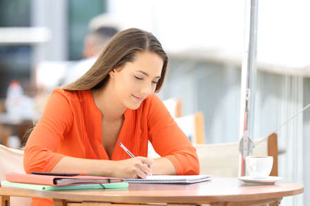 Single serious university student taking notes sitting in a coffee shopの写真素材