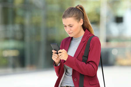 Worried young businesswoman using a mobile phone on the streetの写真素材
