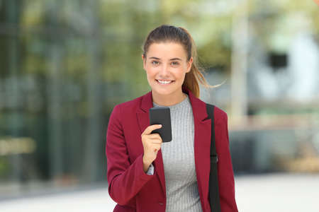 Front view portrait of a young executive holding a mobile phone and looking at youの写真素材